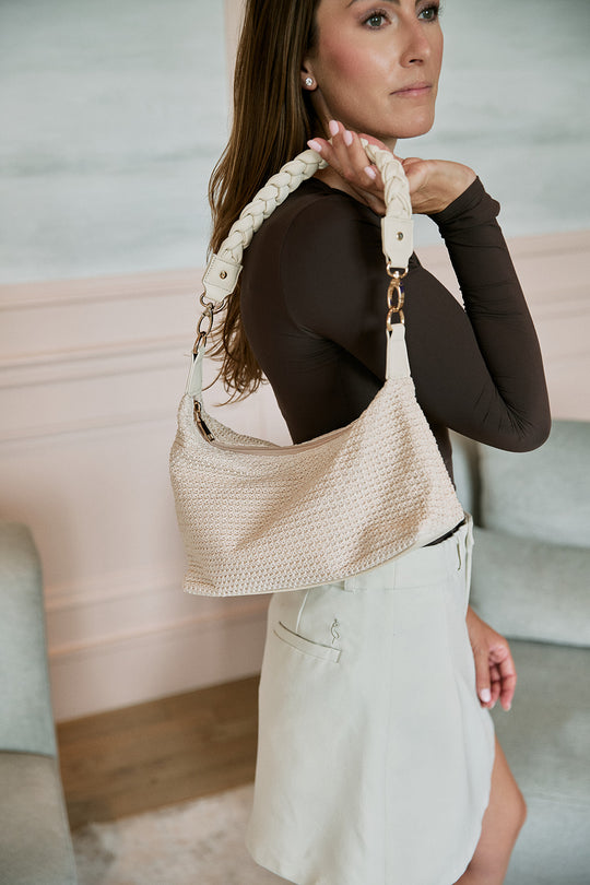 Woman holding a beige woven handbag indoors