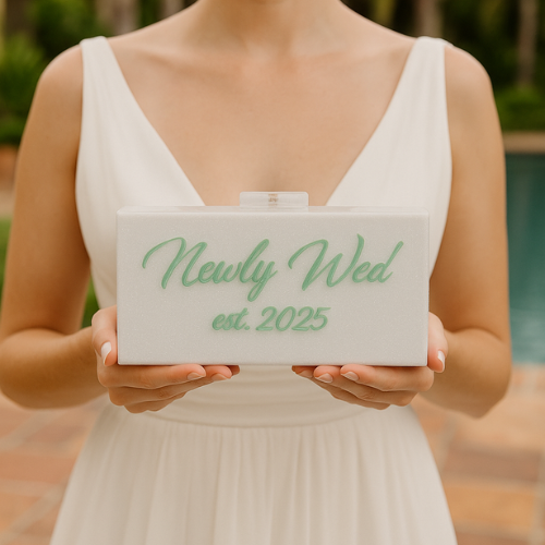 White glitter acrylic clutch with mint green engraved lettering reading “Newly Wed est. 2025”, styled for bridal or wedding day use.